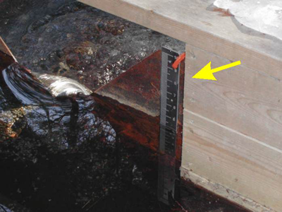 staff gauge mounted to the face of a weir plate to measure head level